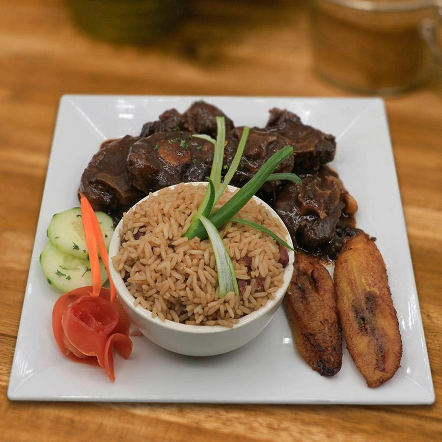 Meat in sauce with rice and vegetables and slices of ripe plantains